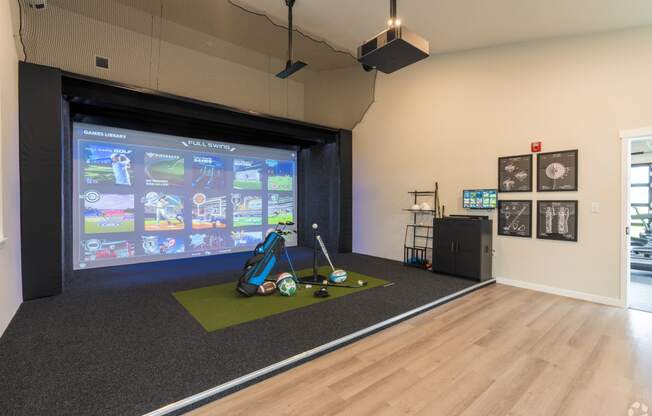 a fitness room with a projector screen and exercise equipment on a green rug
