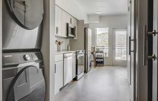 a kitchen with a washer and dryer and a door to a living room