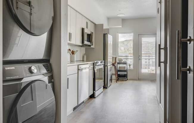 a kitchen with a washer and dryer and a door to a living room