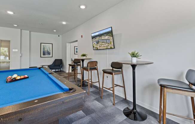 a games room with a pool table and bar with stools