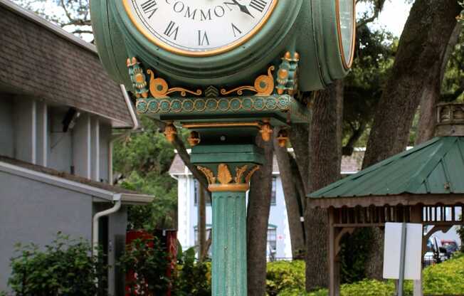 a green clock on a pole in a park