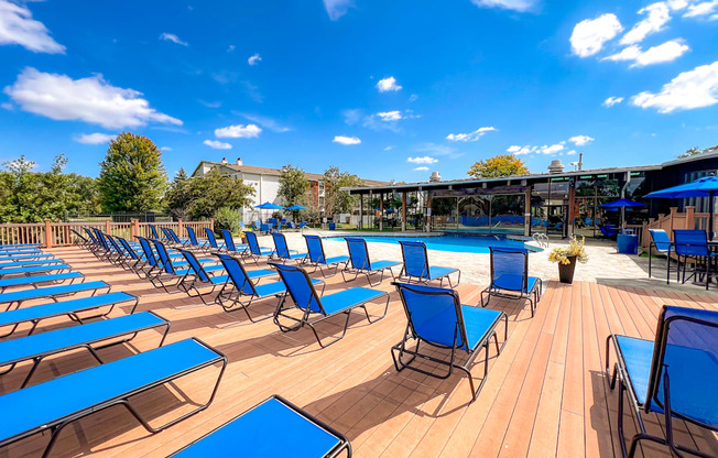 A sunny day at the pool with blue lounge chairs and wooden deck.