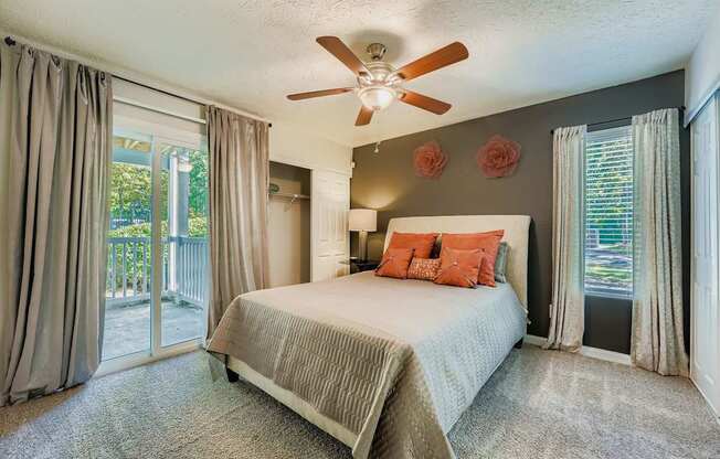 Bedroom with a bed, a ceiling fan, and a sliding glass door.