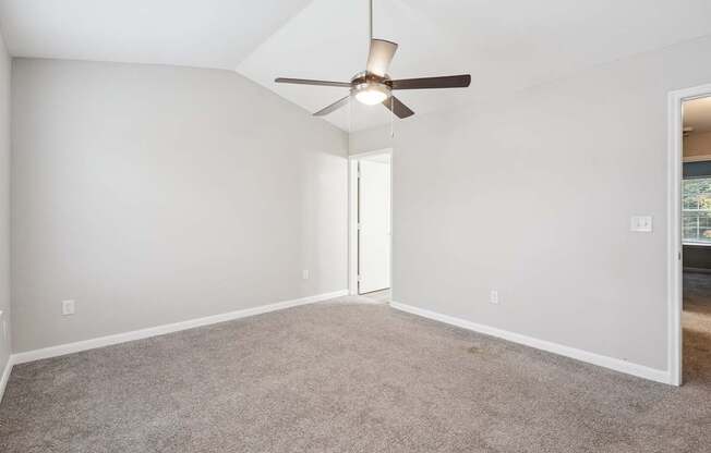 A room with a ceiling fan and carpeted floor.