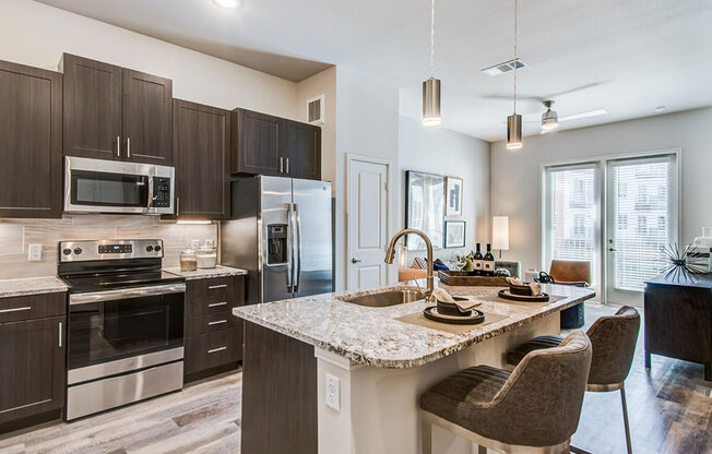 Granite counter tops, stainless appliance package, medium brown cabinets, plank wood-style flooring, island seating, abundant cabinet and pantry space