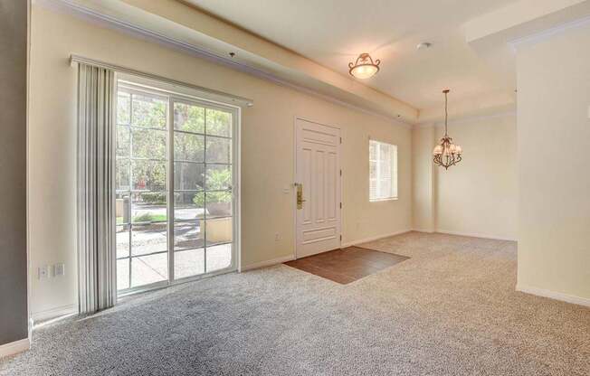 A room with a carpeted floor, a door, and a chandelier.