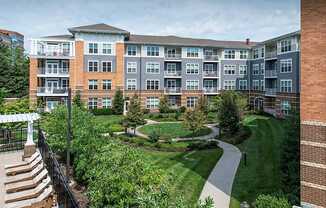 an exterior view of an apartment building with a garden and walkway