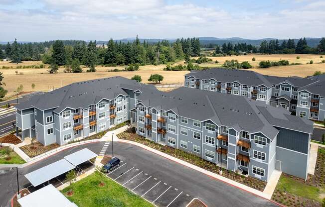 A large apartment complex with a parking lot in front.