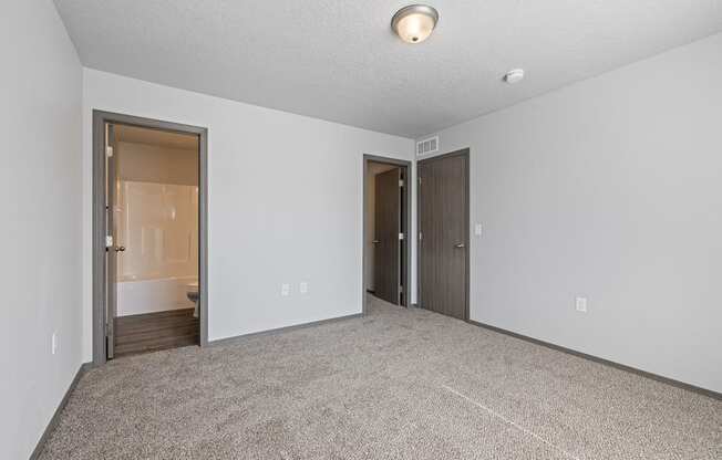 Bright, vacant bedroom with neutral walls and carpet flooring.