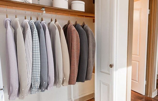 a closet with clothes hanging on a rack and a door to the bathroom