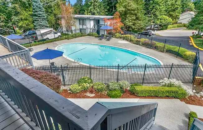 A small pool surrounded by a black fence and a blue umbrella.