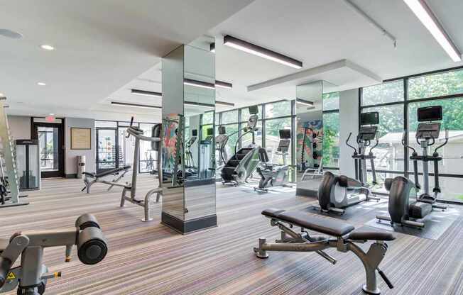 A gym with a variety of equipment including treadmills, weights, and exercise machines.