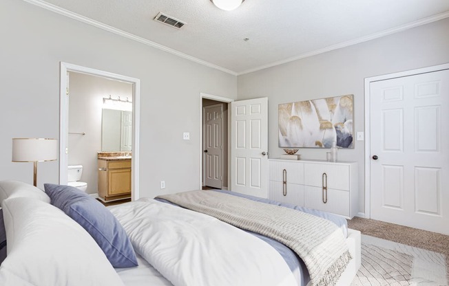 a bedroom with a large bed and a bathroom in the background