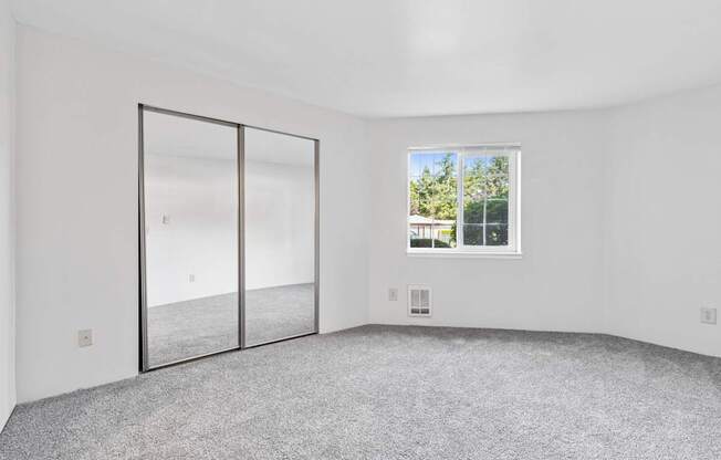 A room with a grey carpet and a large window.