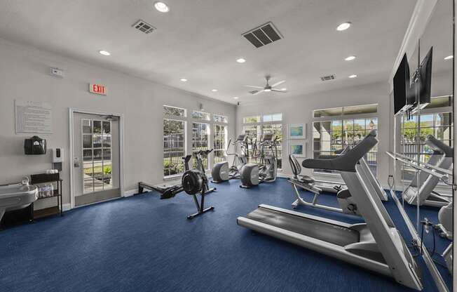 A gym with a variety of equipment including treadmills, exercise bikes, and weight machines.