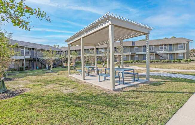 A covered picnic and barbeque area in front of apartment buildings  at The Creole Apartments in Shreveport, LA