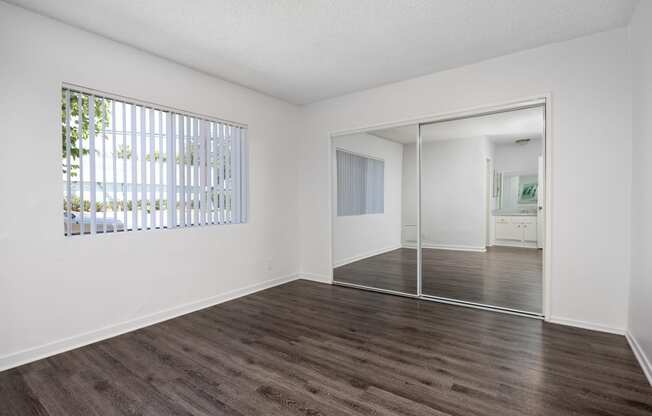 an empty living room with white walls and wood flooring and a sliding glass door