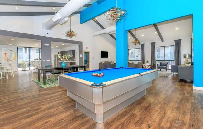 A pool table is in the middle of a room with wood floors.