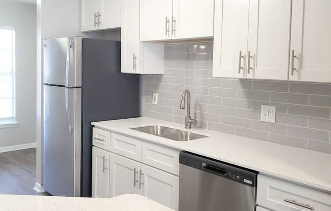 a kitchen with white cabinets and a stainless steel refrigerator