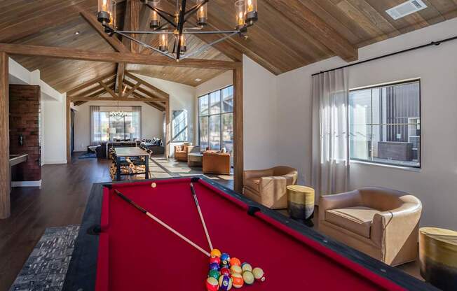 A pool table with a red cloth and a pool cue with a colorful pool ball on it.