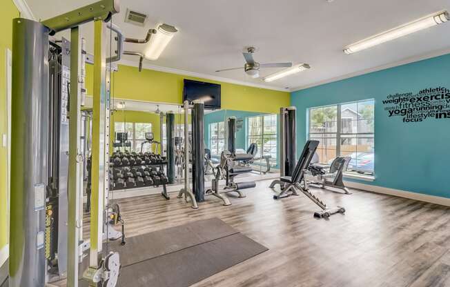 a gym with weights and cardio equipment and a window