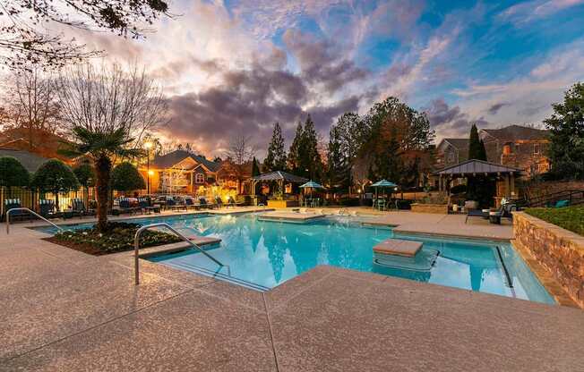 A swimming pool surrounded by a concrete patio and trees.