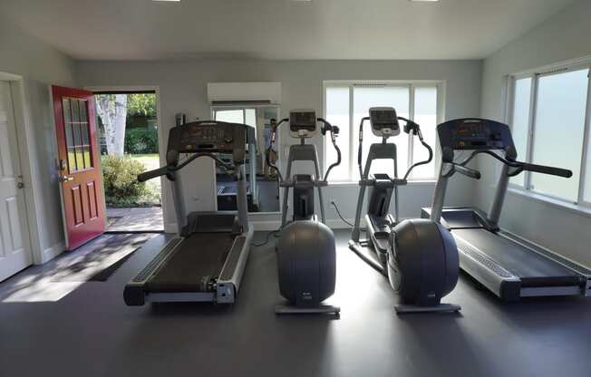 a gym with cardio equipment on the floor and windows