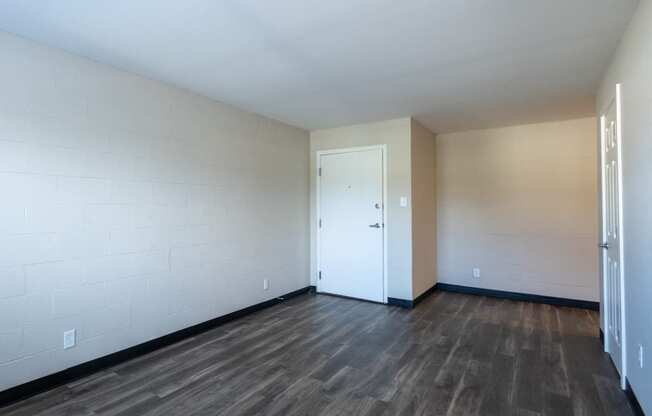 an empty living room with wood flooring and a white door