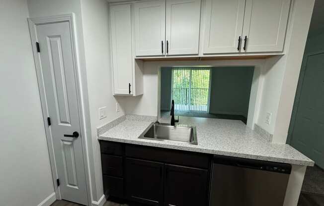 an empty kitchen with white cabinets and a sink