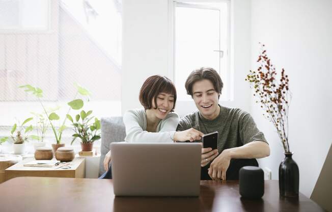 two people sitting at a table looking at a laptop