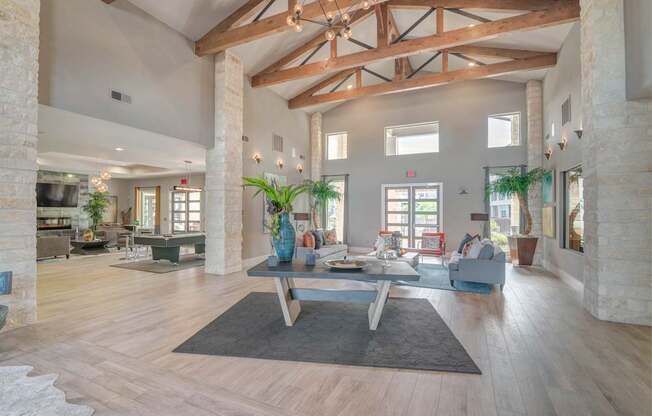 A spacious living room with wooden beams and a central coffee table.