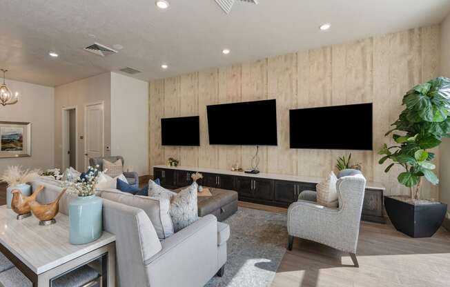 a living room with couches and chairs and televisions on the wall