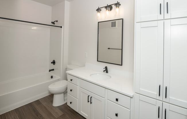 a bathroom with white cabinets and a white toilet and a sink at The Crossings at Windsong, Prescott Valley, Arizona