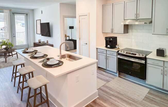 A kitchen with white cabinets and a white island with a sink.