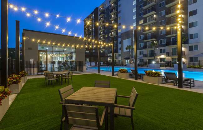 a rendering of a yard with tables and chairs and a pool at night