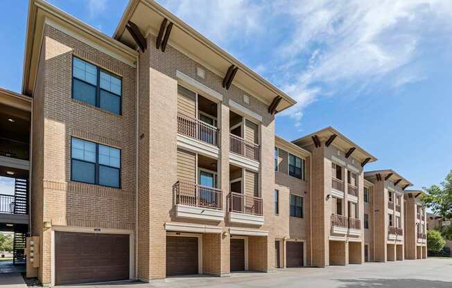 a brick apartment building with garages and a blue sky