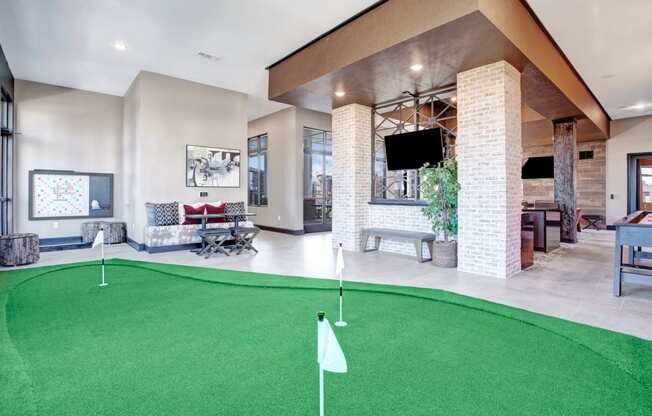 a putting green in the lobby of a clubhouse with a tv