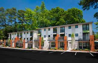 A row of modern townhouses with balconies and trees in the background.