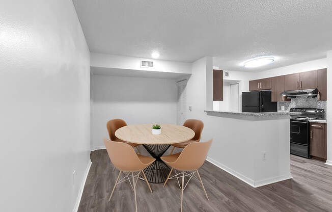 A kitchen with a dining table and chairs in the foreground.