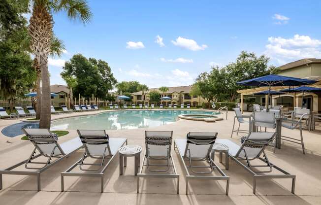 a swimming pool with chairs and umbrellas next to a resort style pool