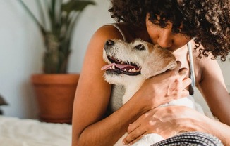 a woman kissing a dog on a bed