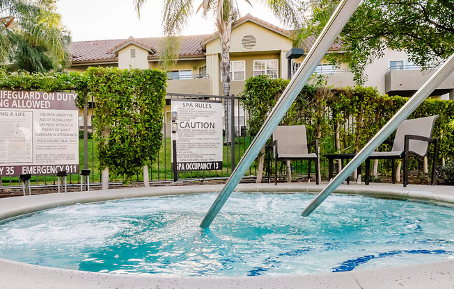 A pool with a sign that says "Lifeguard on Duty" and "Spa Rules".