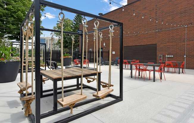 a large wooden table and chairs in a courtyard with a brick building in the background