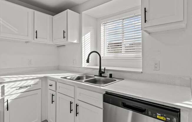 a kitchen with white cabinets and a sink and a window