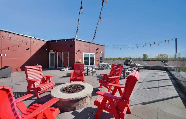A patio with red chairs and a fire pit.