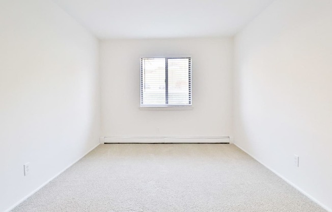 an empty room with a window and white walls