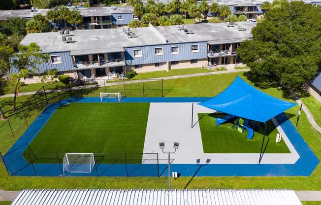 a blue tent is set up on a tennis court in front of a row of houses