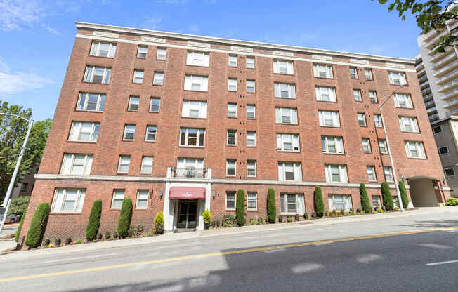 Front Street View of large brick property building with a red awning and a street in front of it at Stockbridge Apartment Homes, Seattle, 98101