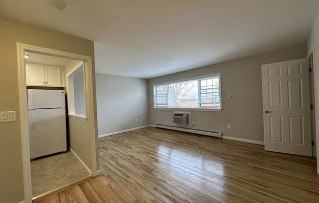 A room with wooden floors and a window with blinds.