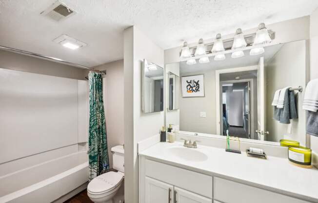 A white bathroom with a toilet, sink, and mirror.